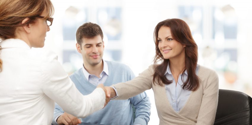 Contemporary young couple get financial advise and shaking hands.