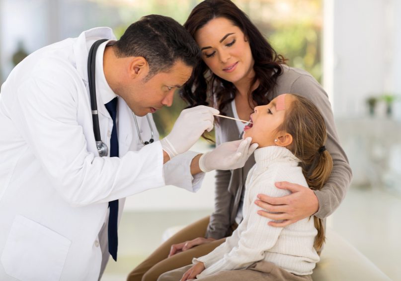 mid age pediatric doctor examining little patient
