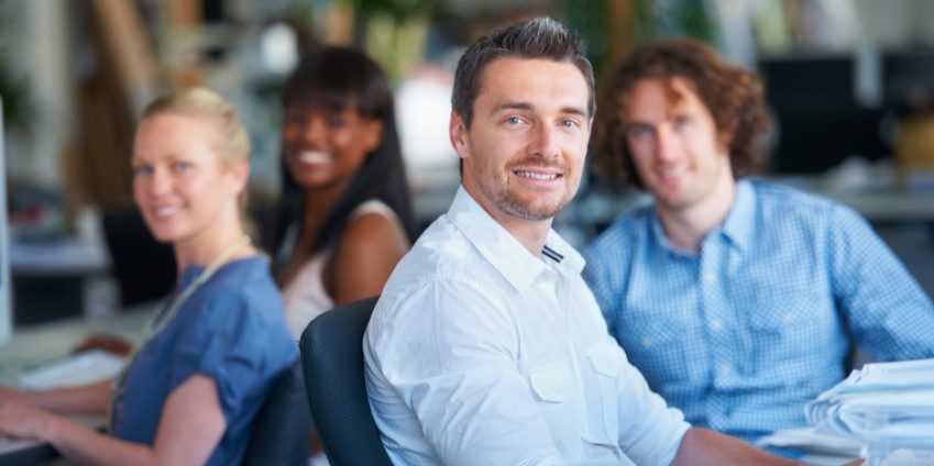 Portrait of four coworkers sitting at their desks